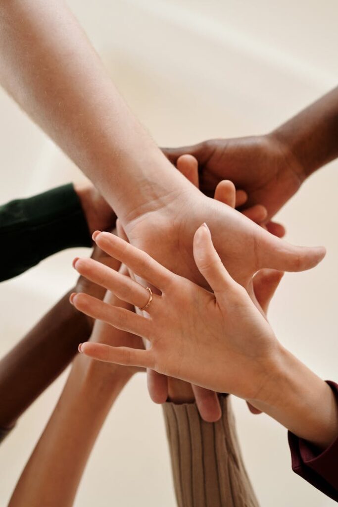 pexels-photo-6146693 A close-up of diverse hands joined together symbolizing teamwork, cooperation, and unity indoors.